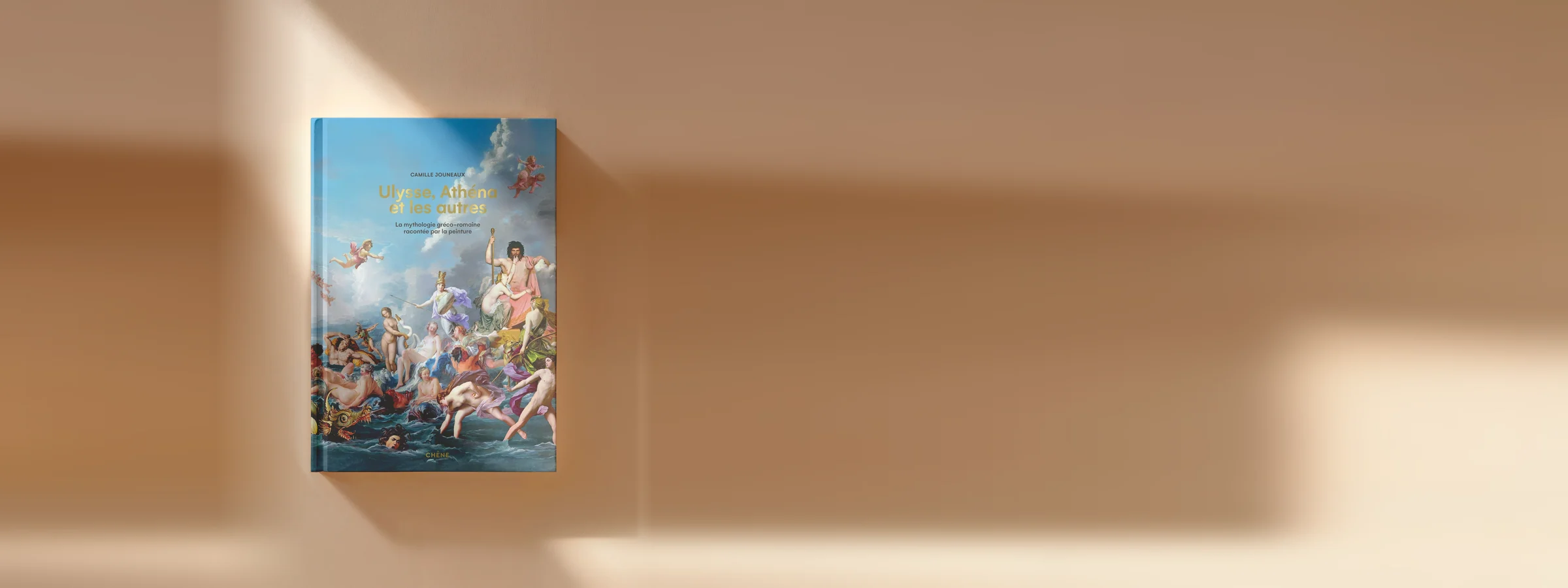 Le livre Ulysse, Athéna et les autres posé sur un fond beige baigné de lumière