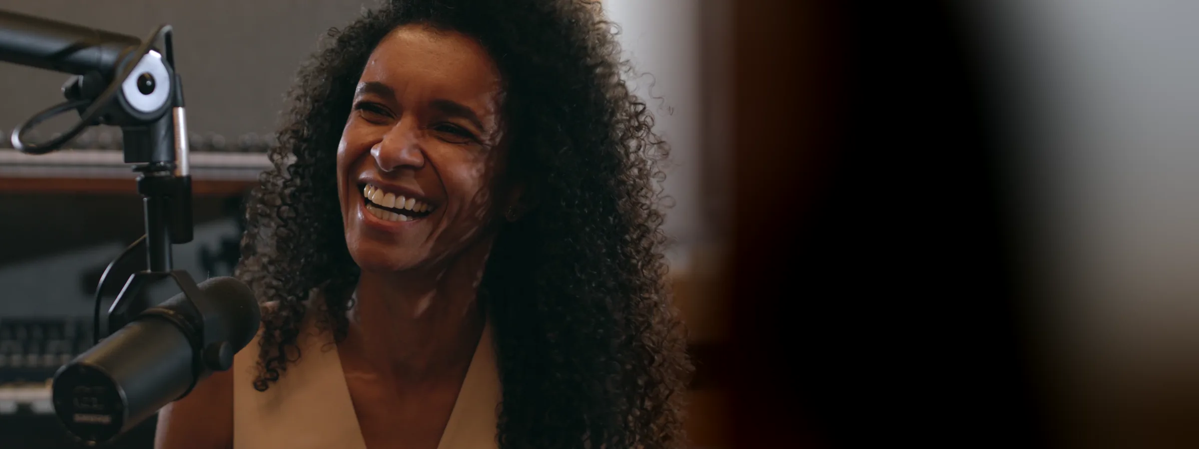 Une comédienne souriante devant son micro, en studio d’enregistrement
