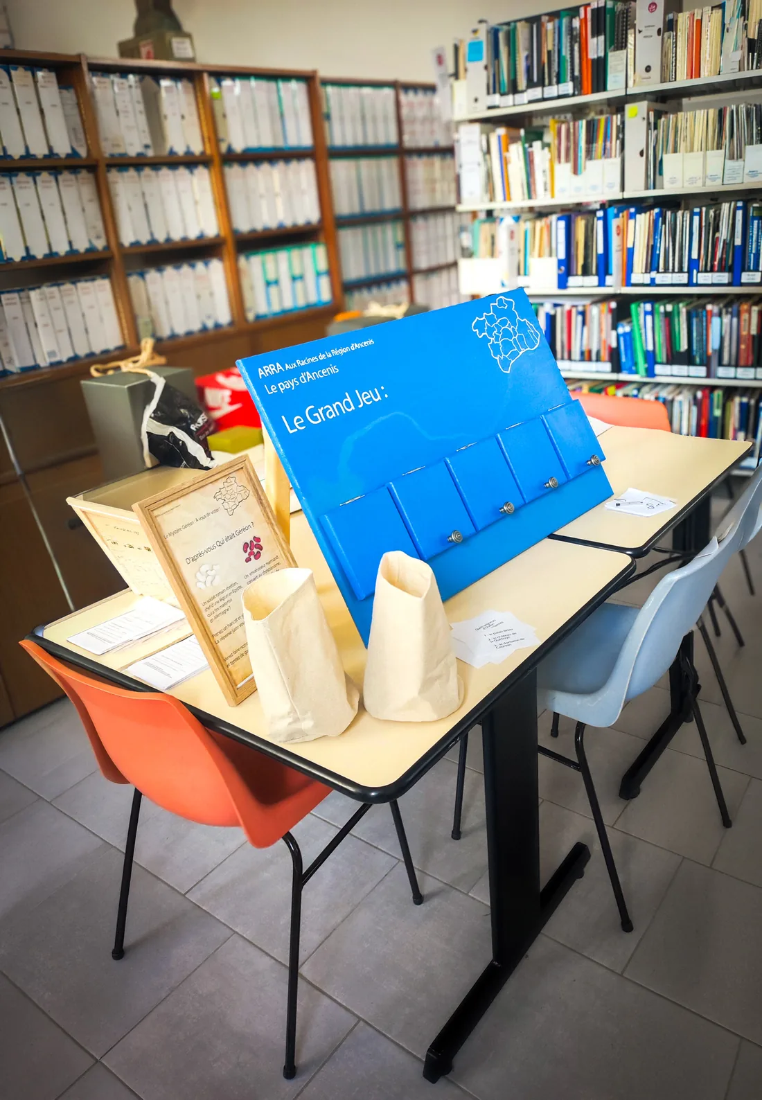 Le Grand Jeu installé sur une table, devant des rayonnages de livres