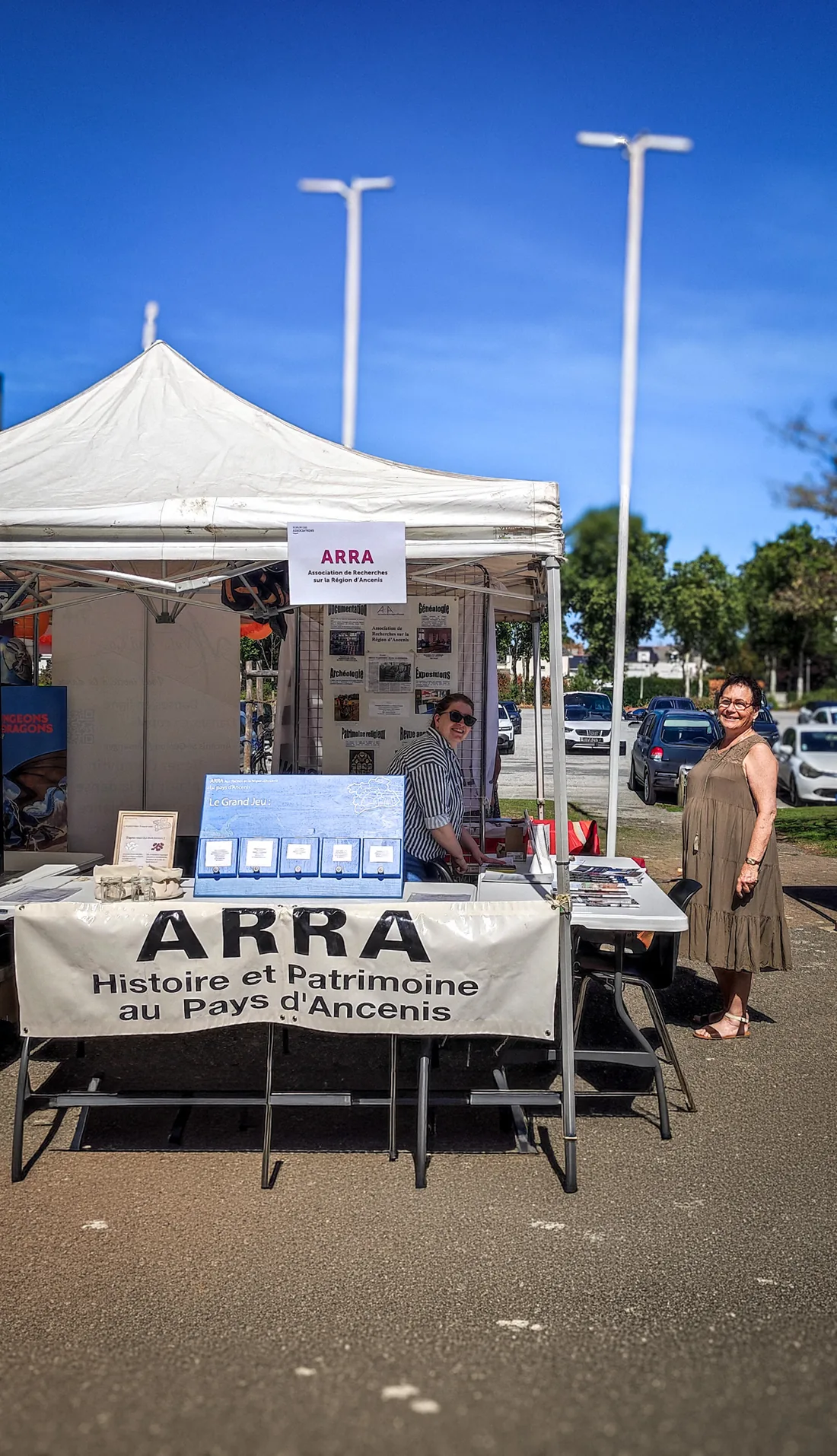 Le stand de l'ARRA sous un grand ciel bleu, deux bénévoles souriantes