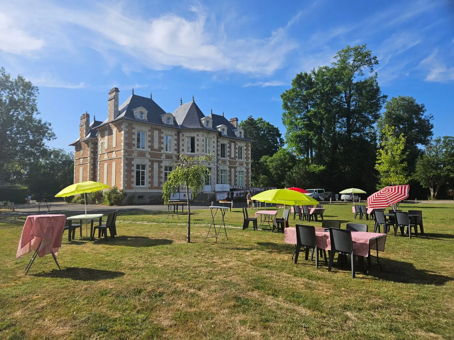 Le Château de la Plinguetière et son parc, tables et parasols installés sur la pelouse